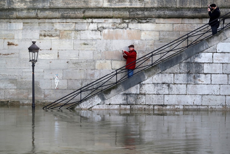 Image: Men take pictures of a street lamp on the flooded banks of the River Seine in Paris