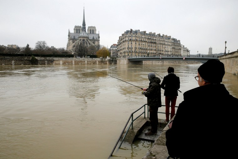 Image: Two men fish on the flooded banks of the River Seine in Paris