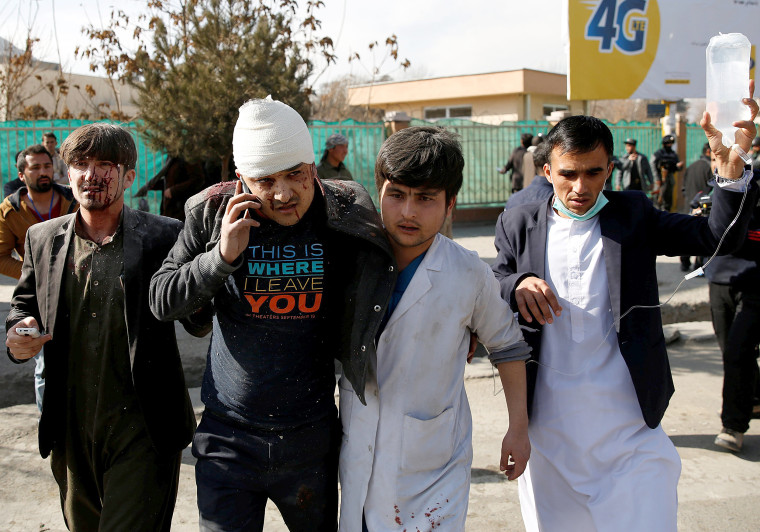 Image: People assist an injured man after a blast in Kabul