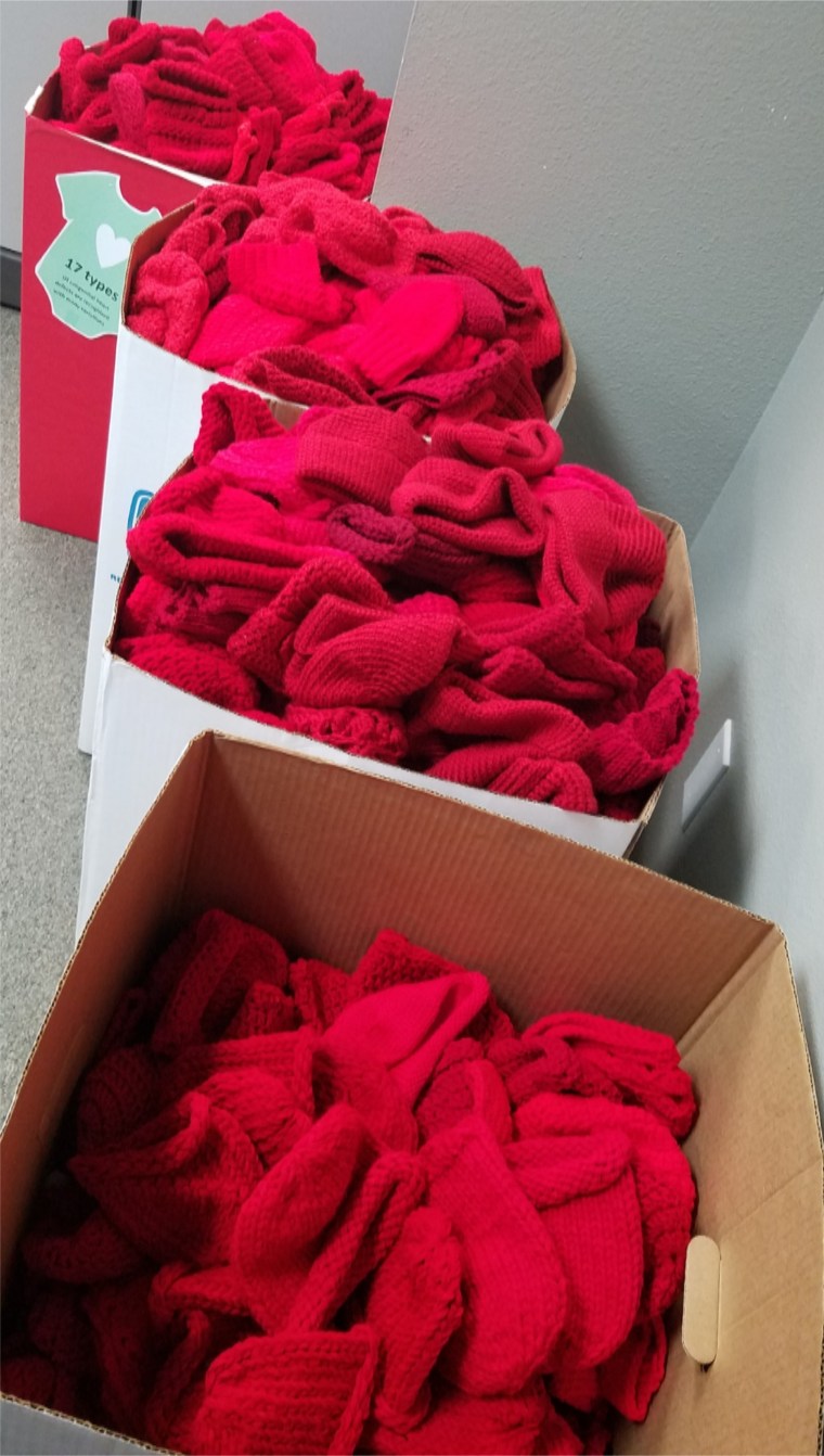 boxes of red caps knitted for babies by volunteers