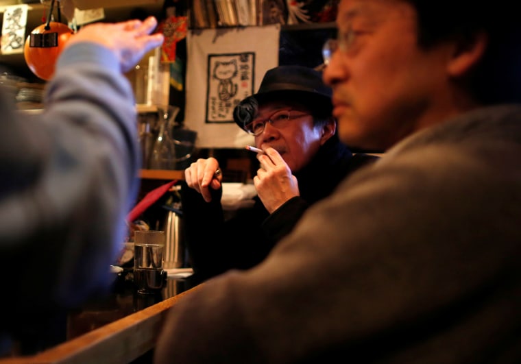 Image: A man smokes at a tavern in Tokyo