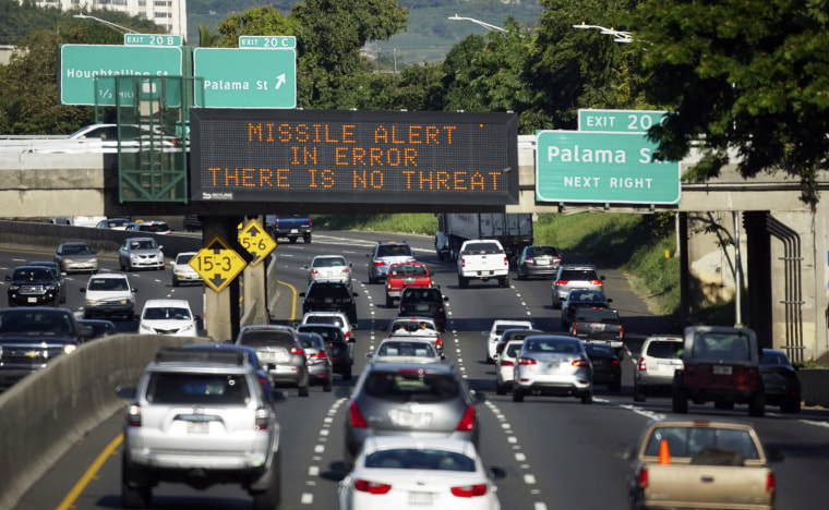Image: Cars drive past a highway sign that reads "MISSILE ALERT ERROR THERE IS NO THREAT"