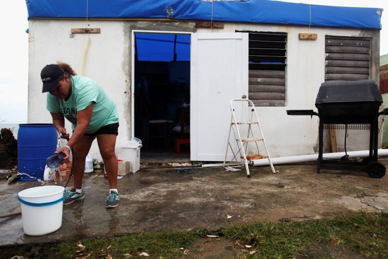 Image: Morales washes dishes in a bucket outside a her home, in Yabucoa