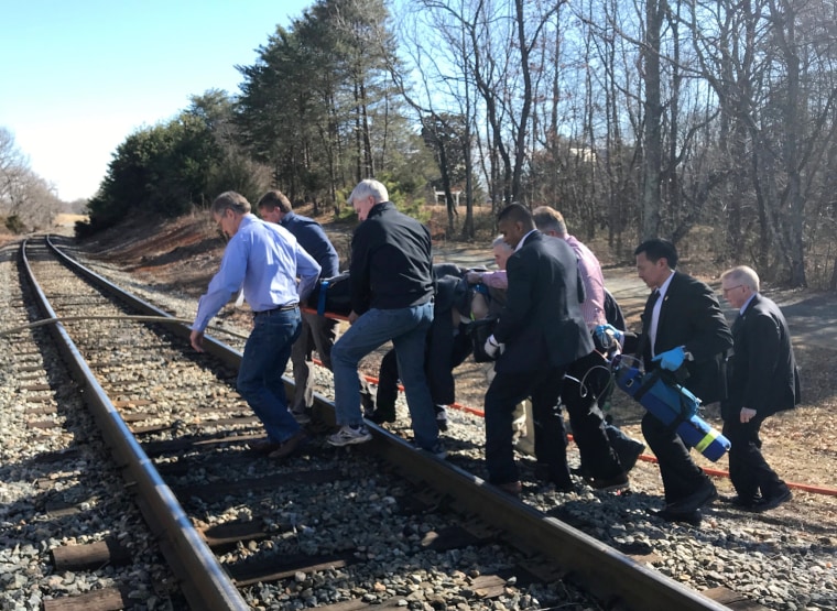 Image: One of the injured is carried across train tracks to an ambulance after a train carrying members of Congress collided with a garbage truck in Crozet, Virginia