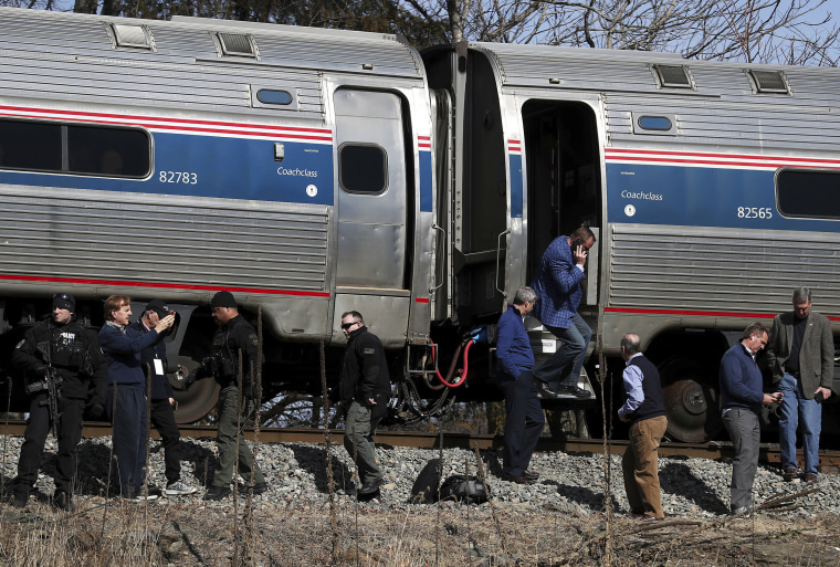 Image: Passengers watch as emergency personnel operate work at the scene of a train crash