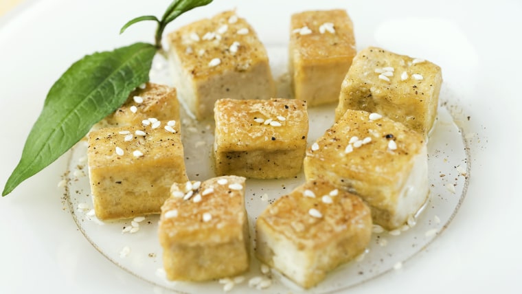 Fried tofu cubes arranged on plate, garnished with sesame seeds