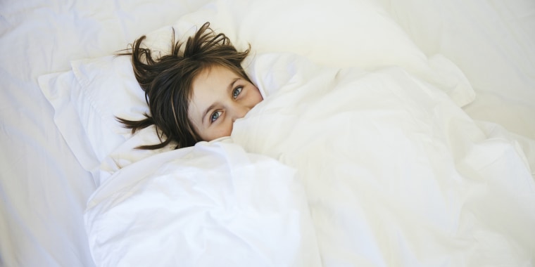 Young girl lying under duvet