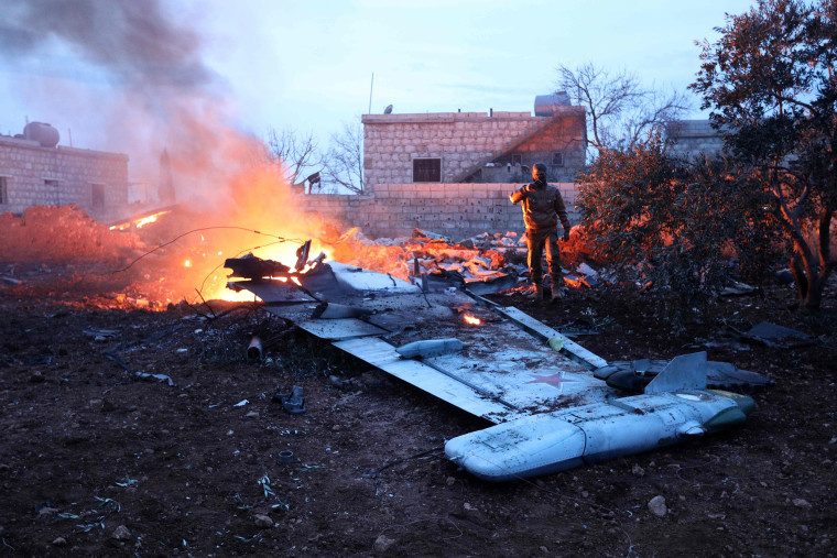 Image: A rebel fighter takes a picture of a downed fighter jet 