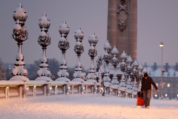 A man drags a suitcase along the Pont Alexandre III bridge during the early morning in Paris on Feb. 7.
