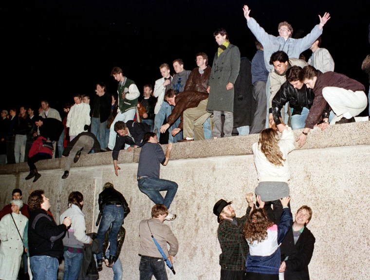 Image: People climb the Berlin wall at the Brandenburg gate