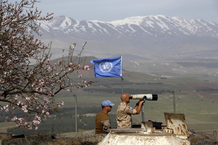 Image: UN members look through binoculars as they monitor the Israel-Syria border in the Israeli-annexed Golan Heights, on Feb. 10, 2018.