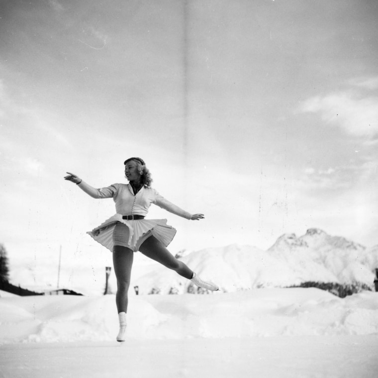 American figure skater, Gretchen Merrill in St Moritz, Switzerland for the 1948 Winter Olympics.  She wairs a flaired skirt and flies when she jumps.