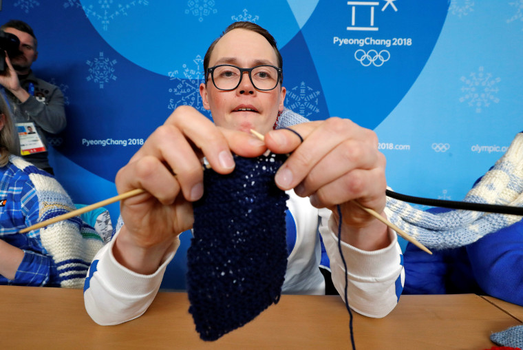 Antti Koskinen, snowboard head coach, shows how he knits, during a news conference in Pyeongchang