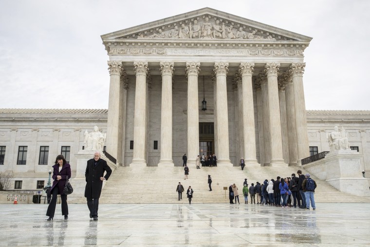 Image: People stands on the plaza of the U.S. Supreme Court in Washington to attend arguments
