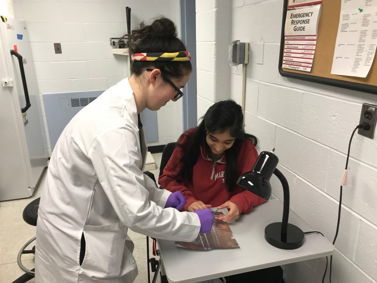 Hannah Weisman, a neurobiology major at the University of Maryland, helps fellow student Namitha Thomas clip her fingernails as part of a study of how flu spreads.