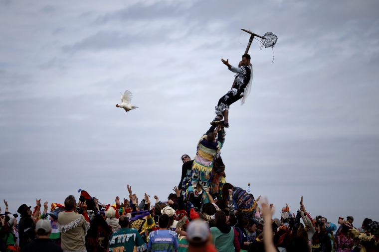 Image: A reveller releases a chicken from a cage after climbing a greased pole during the Faquetaique Courir de Mardi Gras celebration in Eunice