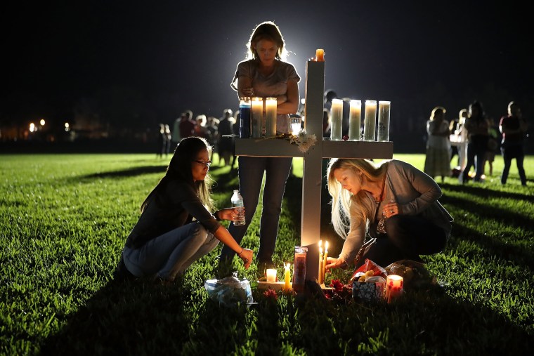 Maria Reyes, Stacy Buehler and Tiffany Goldberg light candles around a cross, as they attend a candlelight memorial service for the victims of the shooting at Marjory Stoneman Douglas High School that killed 17 people, on Feb. 15 in Parkland, Florida.