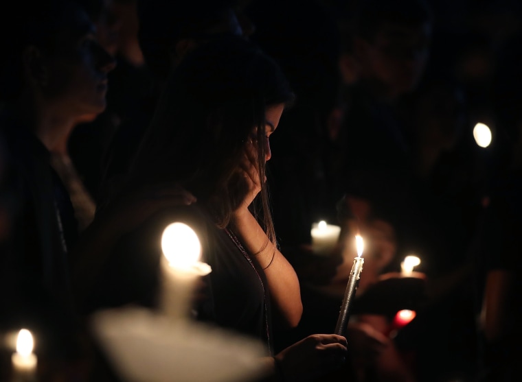 Students and family members grieve at a candlelight vigil.