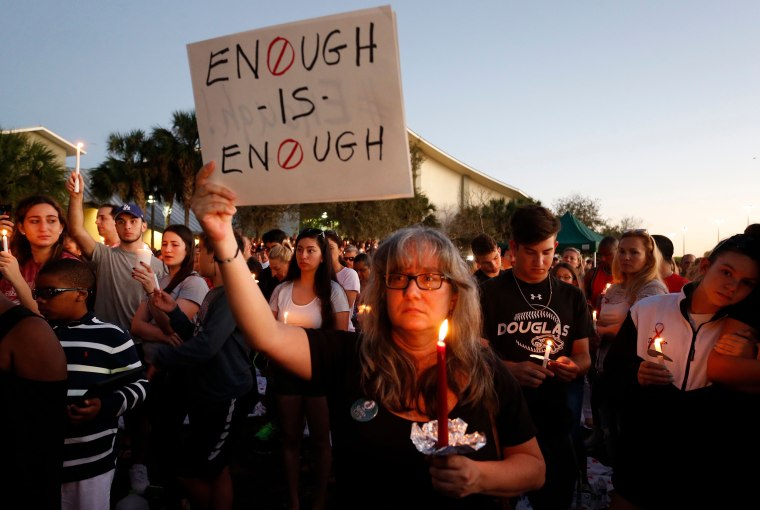 Mourners stand during a candlelight vigil.