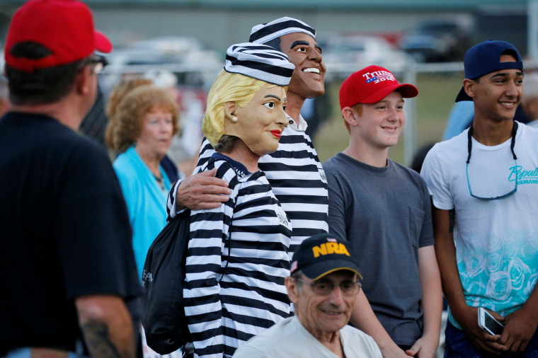 Image: People dressed as Clinton and Obama in prison jumpsuits circulate in the crowd as Trump rallies with supporters in Tallahassee, Florida