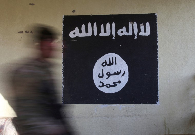 Image: FILE PHOTO: A member of the Iraqi rapid response forces walks past a wall painted with the black flag commonly used by Islamic State militants, during battle in the Wahda district of eastern Mosul, Iraq