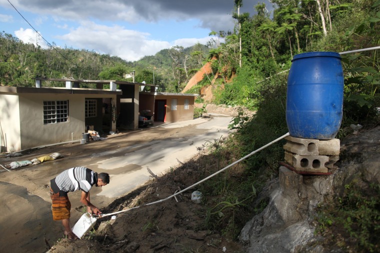 Image: Juan Cosme fills a container with mountain spring water outside his home, after Hurricane Maria hit the island in September 2017, in Utuado