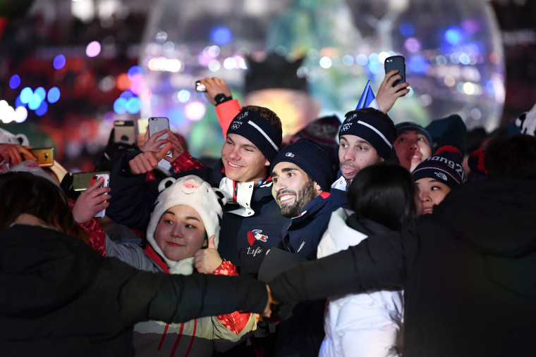 France's biathlon champion Martin Fourcade poses for a selfie with fellow athletes and volunteers.
