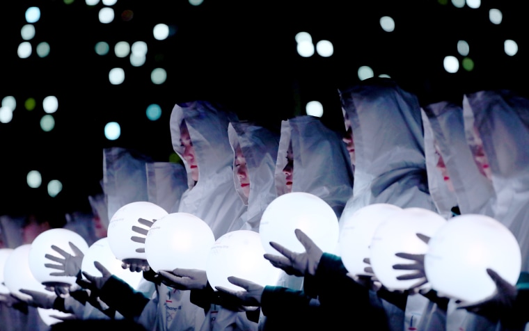 Artists hold light globes in the closing ceremony performance.