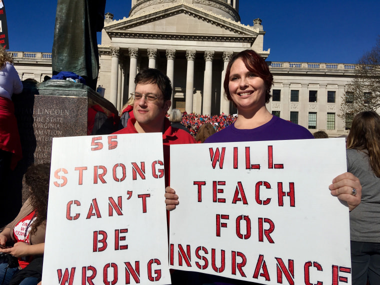 Image: Teachers John and Kerry Guerini of Fayetteville, West Virginia, hold signs