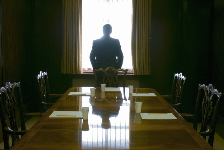 Image: A businessman looks out the window of a meeting room