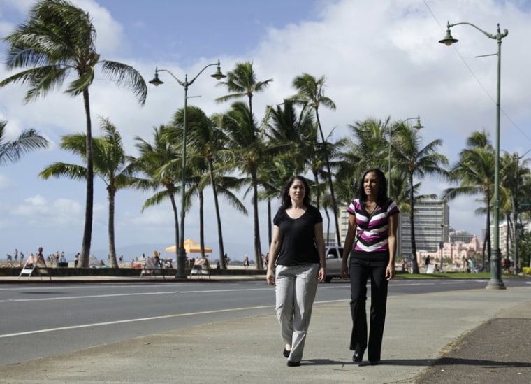Diane Cervelli, left, and Taeko Bufford, right, and walk past Waikiki beach in Honolulu. 