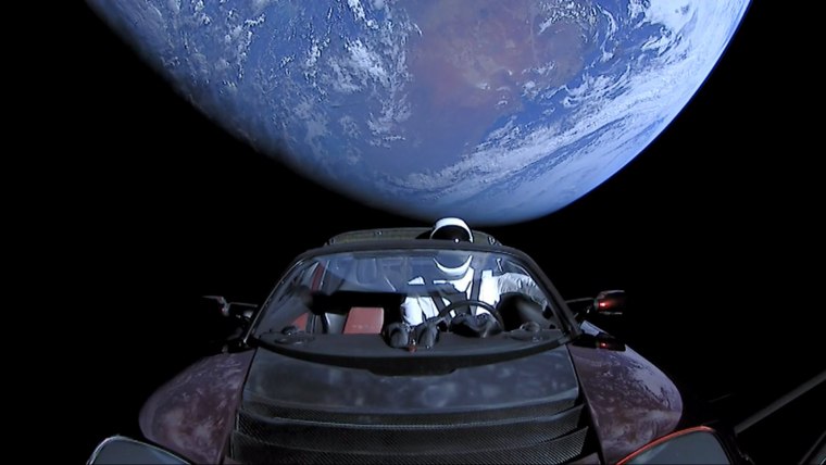 Image: A cherry red Tesla Roadster automobile floats through space after it was carried there by SpaceX's Falcon Heavy