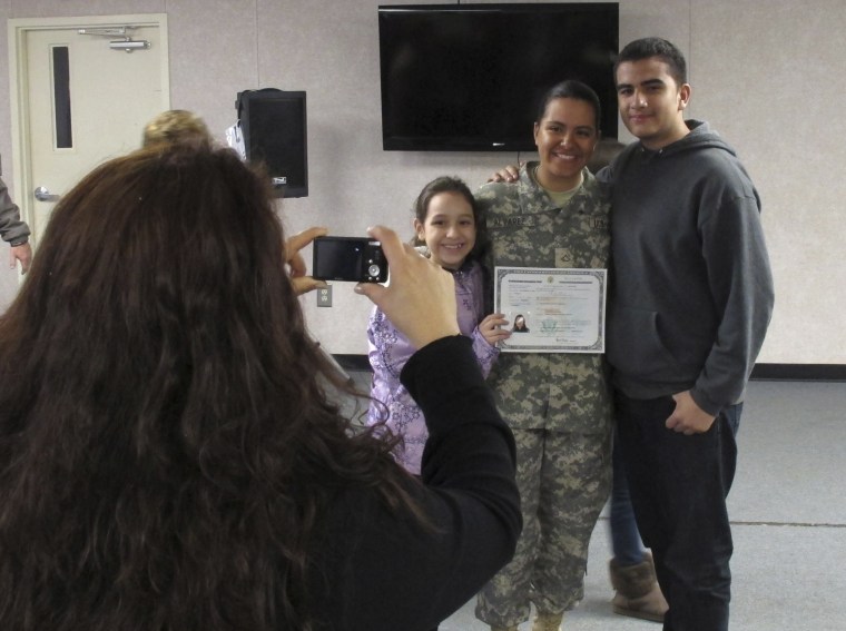Image: Army Pfc. Jennifer Alvarez, center, of Colombia, poses with her family after taking the oath to become a U.S. citizen, at Fort Jackson, S.C.