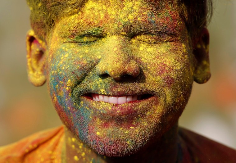 Image: A student of Rabindra Bharati University, with his face smeared in coloured powder, reacts as his fellow student throws coloured powder on his face during Holi celebrations inside the university campus in Kolkata