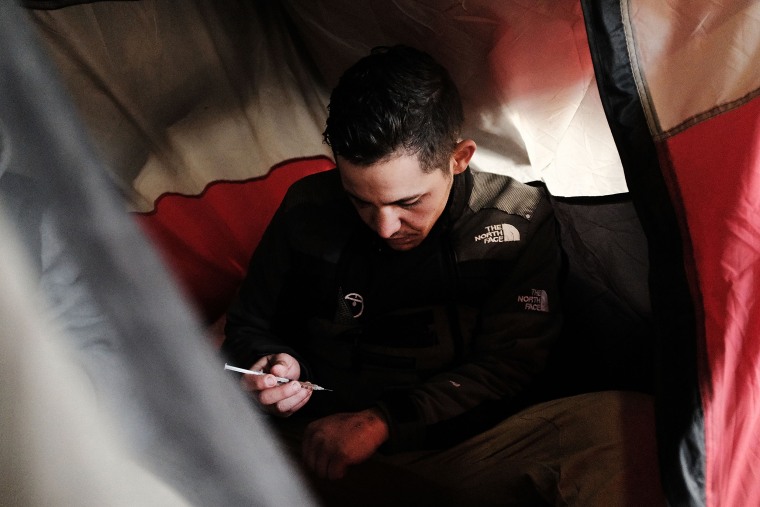Image: A man uses heroin in a tent