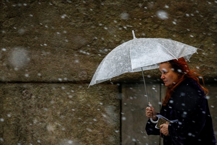 Image: A woman walks through the snow in the financial district during a winter nor'easter in New York