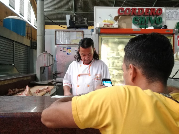 Ruben Sosa, behind the counter, helps a customer at the meat department of a Caracas supermarket.