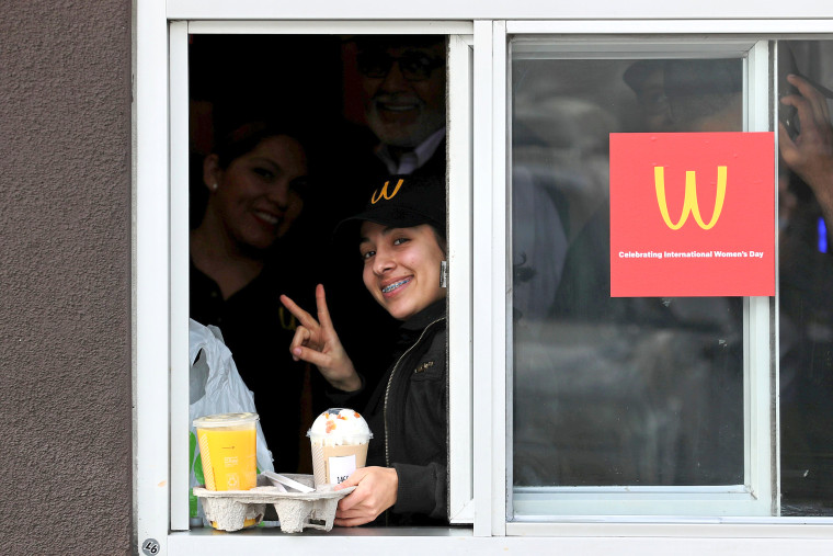 Image: A worker works at drive through window as McDonald's iconic 'M' logo is turned upside down in honour of International Women's Day in Lynwood