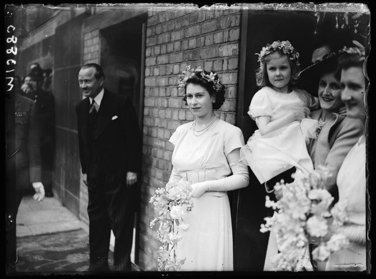 Wearing a simple ankle-length dress and garland of flowers in her hair, Princess Elizabeth serves as bridesmaid to friends at the Savoy Hotel in London in May 1946.