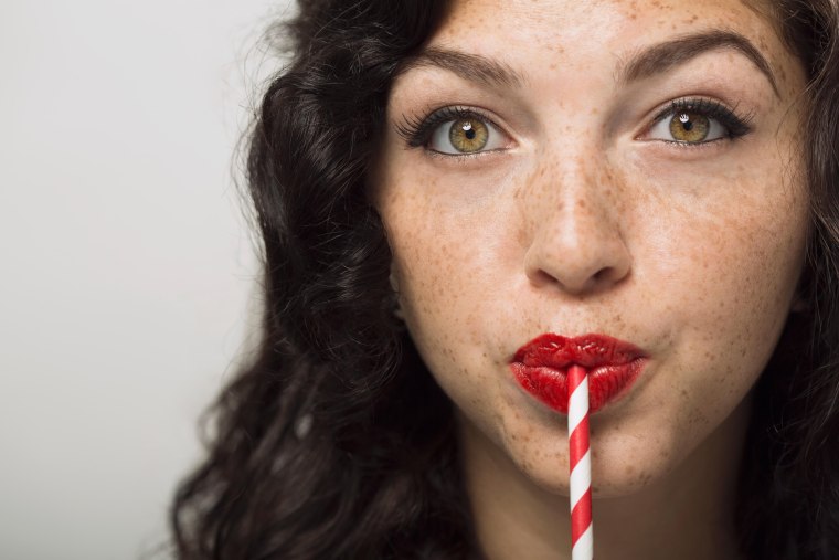 Image: A woman drinks with a straw