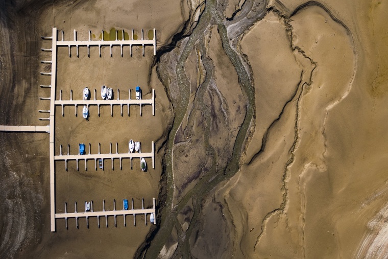 Image: Stranded boats sit at a dock along the shoes of the Lake of Gruyere