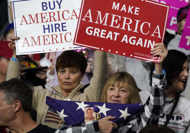 Image: A supporter holds an American flag with a Purple Heart medal pinned to it as U.S. President Donald Trump speaks in support of Republican congressional candidate Rick Sacconne during a Make America Great Again rally in Moon Township
