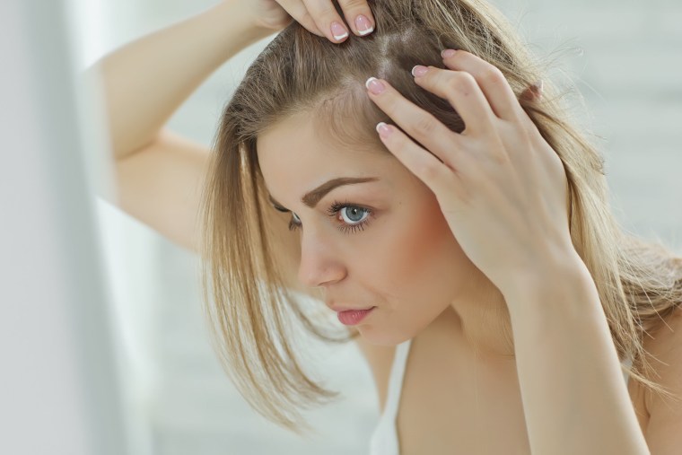 Woman checking hair in mirror.