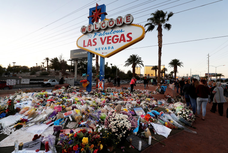 Image: The \"Welcome to Las Vegas\" sign is surrounded by flowers and items, left after the October 1 mass shooting, in Las Vegas