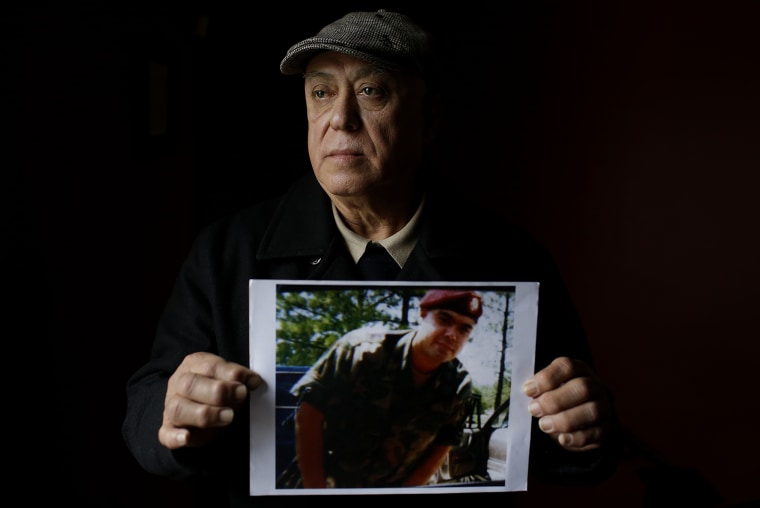 Image: Miguel Perez poses as he holds a photo of his son Miguel Perez Jr.