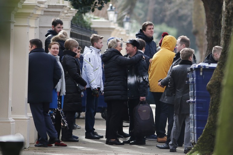 Image: People hug as they carry luggage leaving the Russian Embassy in London