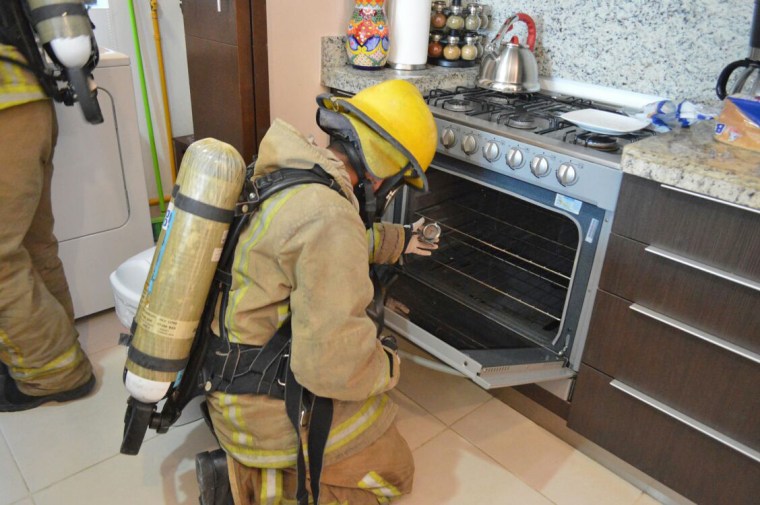 A firefighter examines a gas stove in the rented condo where an Iowa couple and their two children died in Tulum, Mexico.