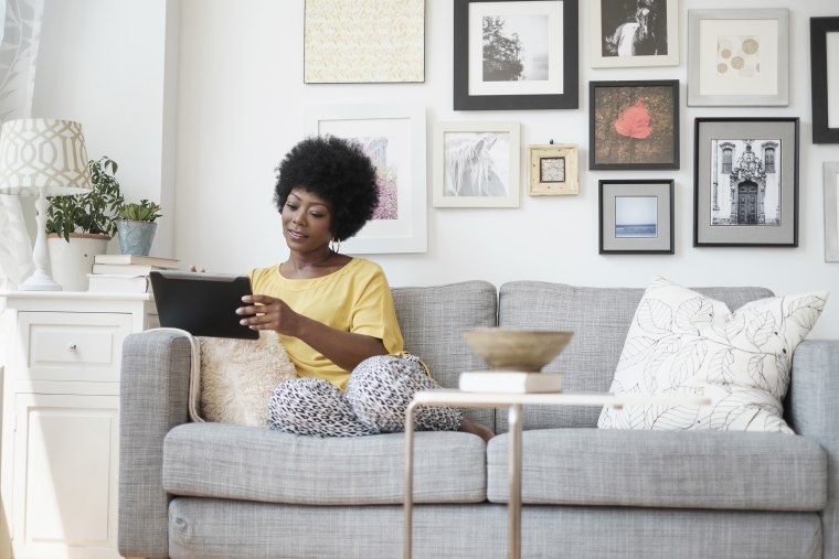 Image: African American woman using digital tablet on sofa