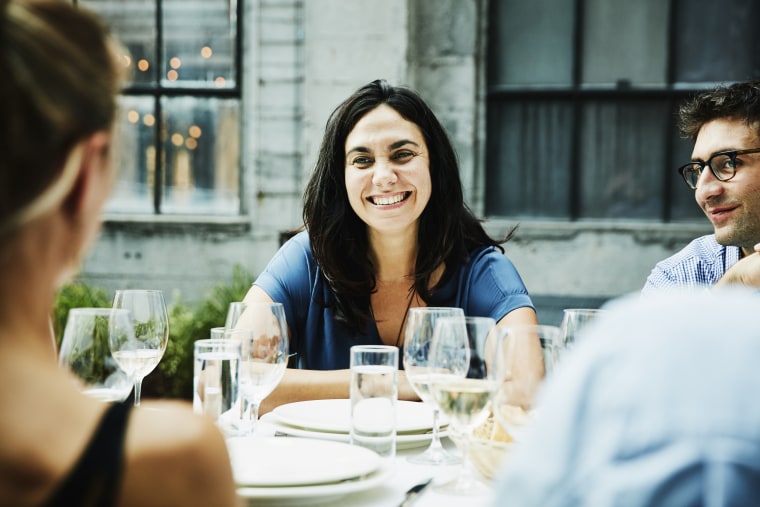 Smiling woman hanging out with friends during dinner on restaurant patio