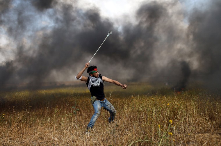 Image: A protester hurls stones at Israeli troops during clashes along the Israeli border with Gaza